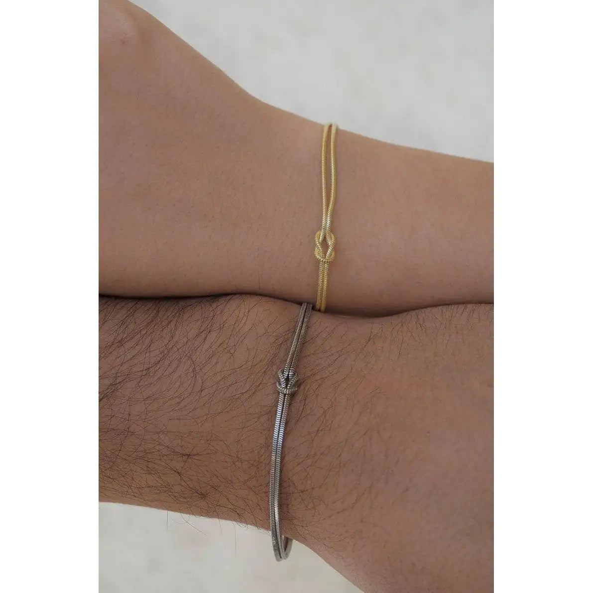 Couple wearing The Bond Set — matching 925 sterling silver bracelets, silver and gold, his and hers