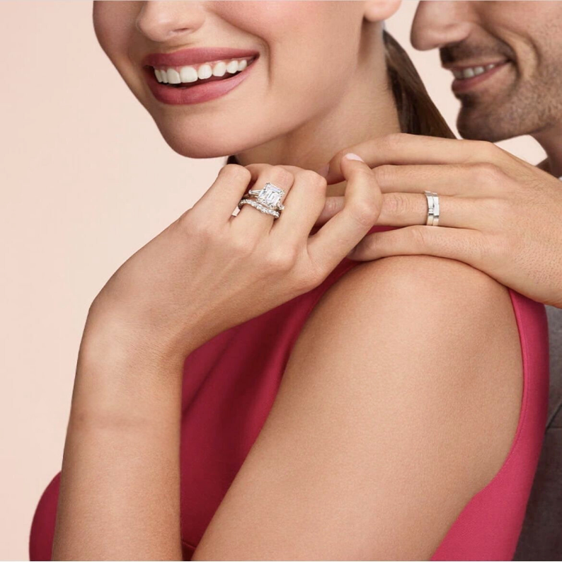 Close-up of a couple wearing diamond rings on a soft pink background